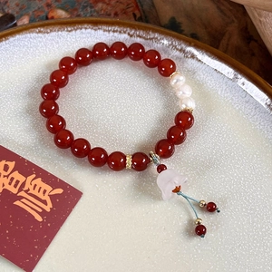 Détail de perles d'agate rouge et perles d'eau douce avec pendentif fleur sur assiette
