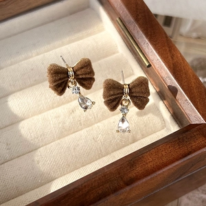 Detailed close-up of brown velvet bow earrings with teardrop crystal drop and gold hardware