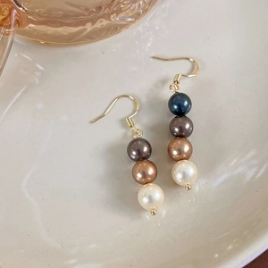 Détail de boucles d'oreilles perles vintage avec perles quadricolores sur un plateau