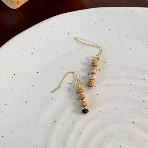 Detail view of retro beaded drop earrings with tiger eye stone and gold hook