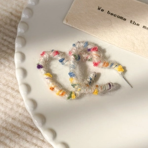 Gros plan de boucles d'oreilles cœur en laine multicolore avec texture tricotée douce