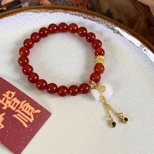 Détail du bracelet en agate rouge avec pendentif Fu doré et breloque en jade blanc
