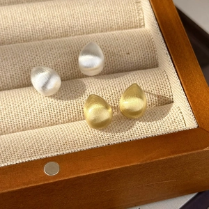 Orecchini a goccia minimalisti in oro e argento satinato su un vassoio per gioielli