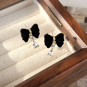 Detail of velvet bow earrings with water drop crystal charms in a wooden jewelry box