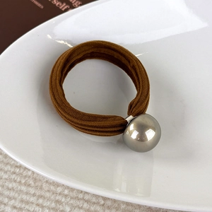 Gros plan sur l'élastique à cheveux marron café avec un pendentif sphérique argenté