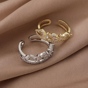 Detailed macro shot of gold and silver leafy rings with zircon on brown silk background