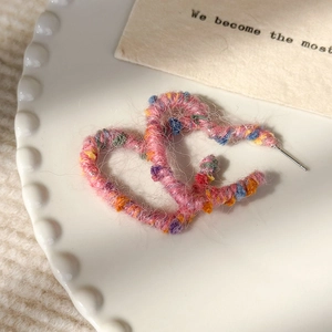 Vue macro de boucles d'oreilles en forme de cœur en laine colorée sur assiette blanche