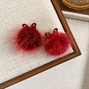 Close-up of fluffy dark red faux mink fur hair clips with ribbon bows for winter