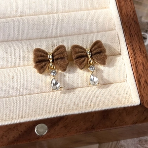 Detailed macro of burgundy velvet bow earrings with sparkling crystal water drop pendants