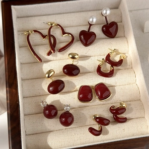 Detailed collection of vintage burgundy enamel heart earrings and pearl studs in a jewelry box