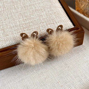 Close-up of brown plush butterfly earrings with soft fur balls and warm texture