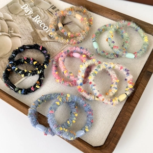 Plush colorful elastic hair ties with resin beads displayed in a wooden jewelry tray