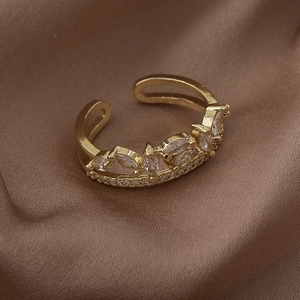 Close-up of golden leaf crown ring with micro-set zircon stones on luxury silk background