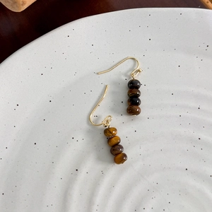 Detail of vintage tiger eye stone beaded earrings with polished gold-plated hooks