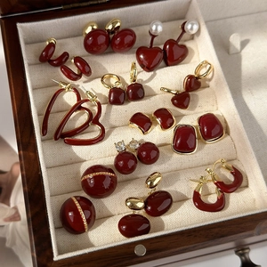 Detail view of vintage dark red enamel heart and geometric earrings in a jewelry box