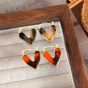 Detailed close-up of heart-shaped hoop earrings with brown and orange tortoise patterns