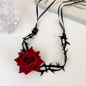Close-up of deep red velvet rose and black thorn choker necklace with silk ribbons