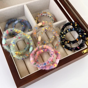 Colorful knitted elastic hair ties with beads in a wooden box for cozy autumn styling