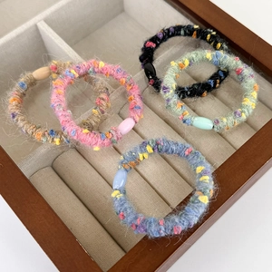 Set of five colorful knit tweed hair scrunchies displayed in a wooden organizer box