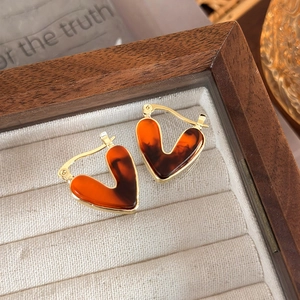 Detail of vintage heart-shaped gold earrings with amber resin on wooden box