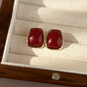 Close-up of vintage gold-plated earrings with deep red cabochon stones on jewelry box