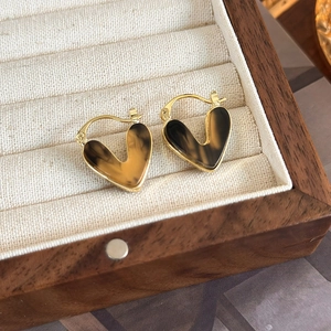 Detailed macro view of heart-shaped gold hoops with tortoiseshell resin in a wooden box