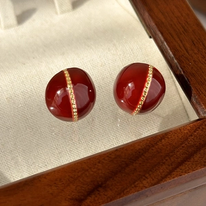 Detailed close-up of dark red enamel ball earrings with elegant gold beaded vertical line