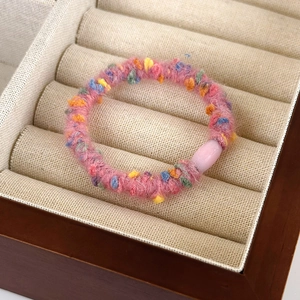 Detailed macro view of a colorful plush hair tie with soft faux fur and resin buckle