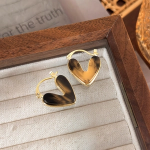 Macro shot of vintage heart hoop earrings with tortoise shell inlay on a jewelry tray