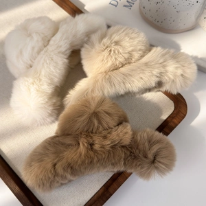 Detail of plush faux rabbit fur hair claws in cream and brown on a wooden tray