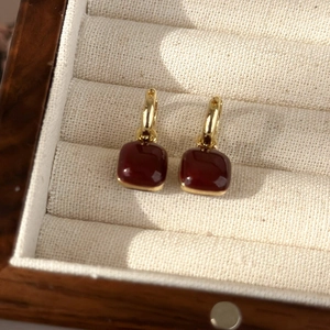 Macro detail of vintage gold heart earrings with deep red geometric enamel inlay