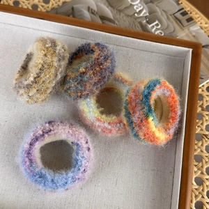Détail de cinq chouchous en peluche aux textures de peinture à l'huile dans un plateau en bois