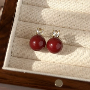 Close-up of red enamel heart earrings with gold claw setting and sparkling zircon