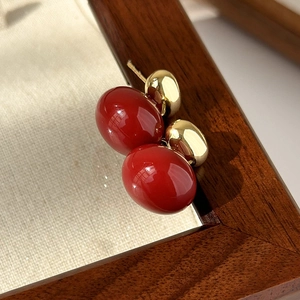 Detail of red enamel heart drop earrings with gold metallic finish and stud backing