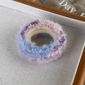 Détail d'un chouchou en peluche dégradé montrant la texture douce du mohair sur un plateau
