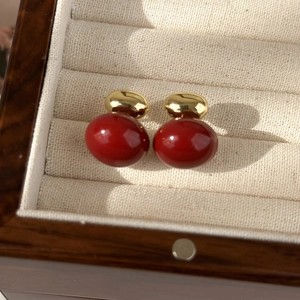 Macro shot of French vintage red glazed heart earrings on beige velvet jewelry box
