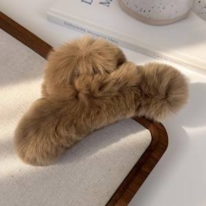 Detailed view of large brown faux fur claw clip with soft texture on wooden tray