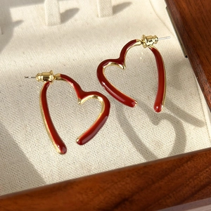 Close-up of vintage gold hollow heart earrings with deep red enamel in a jewelry box