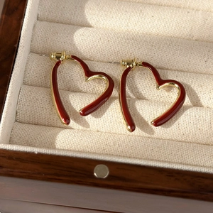 Macro shot of retro heart-shaped red enamel earrings with elegant gold metallic borders