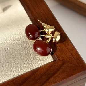 Close-up of vintage dark red enamel heart earrings with gold plating on a wooden box