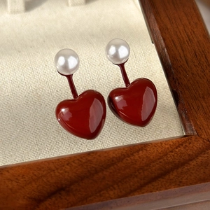 Detailed view of dark red heart earrings with white pearls on a neutral jewelry tray