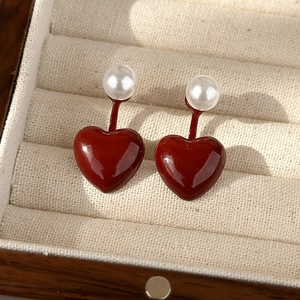 Macro shot of elegant deep red heart earrings with pearls in a beige jewelry box