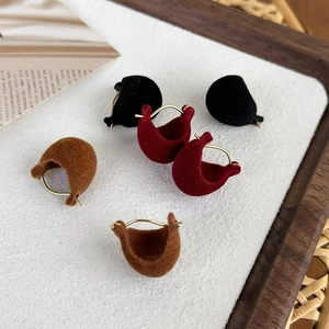 Flat lay of elegant velvet C-shaped hoop earrings in black, wine red, and brown colors