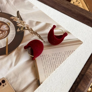 Detail of burgundy flocked velvet hoop earrings placed on a vintage style coffee magazine