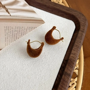 Close-up of elegant dark brown velvet drop earrings with luxury gold-toned metal hooks