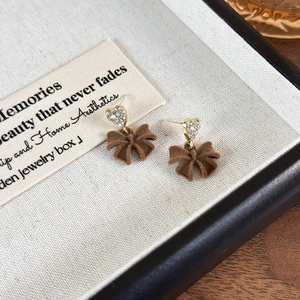 Detail of vintage red velvet bow earrings with rhinestone heart studs in a gift box