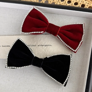 Close-up of red and black velvet bow hair clips with rhinestones in a luxury tray