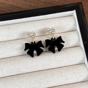 Close-up of velvet bow earrings with heart-shaped rhinestone studs in a jewelry display box