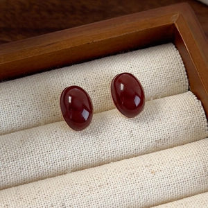 Detail of vintage oval dark red gemstone stud earrings set in gold on a wooden box