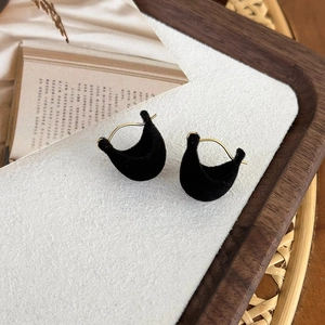 Close-up of black velvet crescent earrings on a vintage wooden tray with dry flowers
